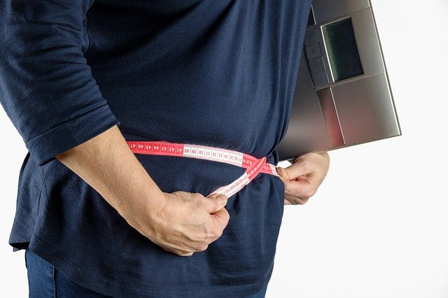 obézní člověk s váhou v ruce